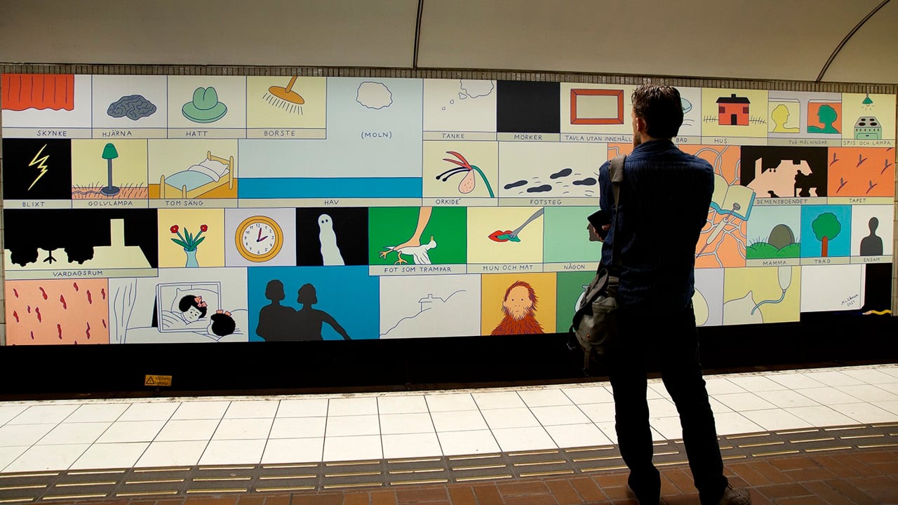 Man som står och tittar på en väldigt lång bild på spårvägg i tunnelbanan.