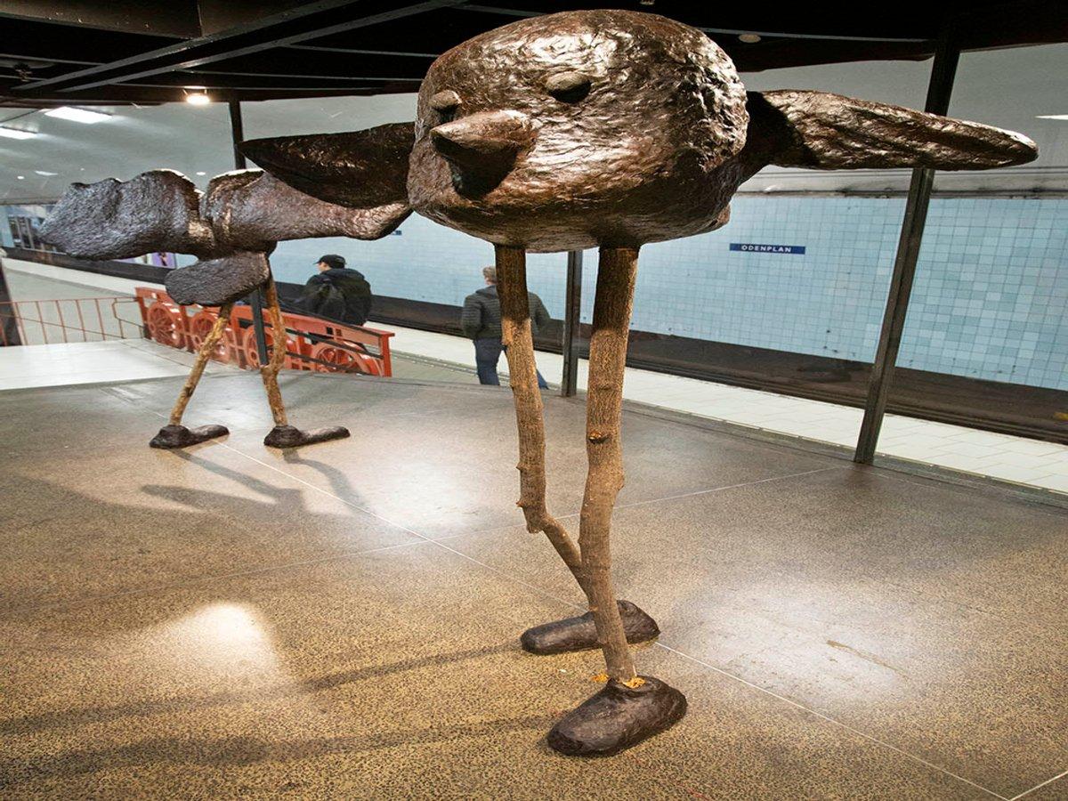 närbild skulptur i montern. Ett stort fågelhuvud på långa ben.